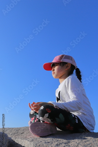 岩場に座り瞑想している少女