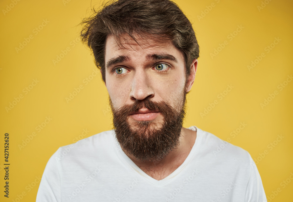 man on a yellow background in a white t-shirt sad face beard model man on a yellow background in a white t-shirt sad face beard model