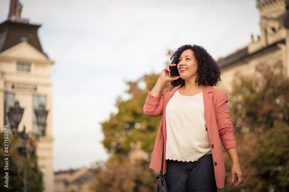 Business woman standing on street and talking on phone.