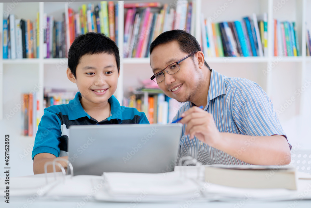 Young teacher helping his student to use a laptop Young teacher helping his student to use a laptop