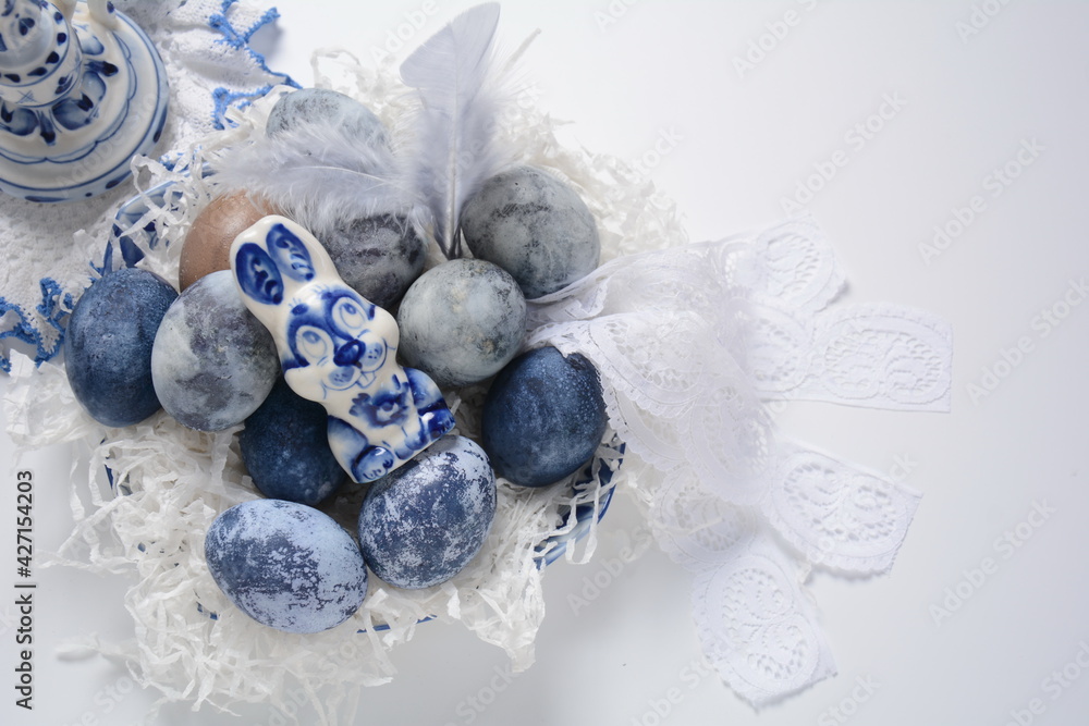 Easter table setting. A bunny and decorated Easter eggs in an Easter basket Easter table setting. A bunny and decorated Easter eggs in an Easter basket