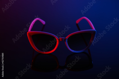 Stylish sunglasses on dark color background