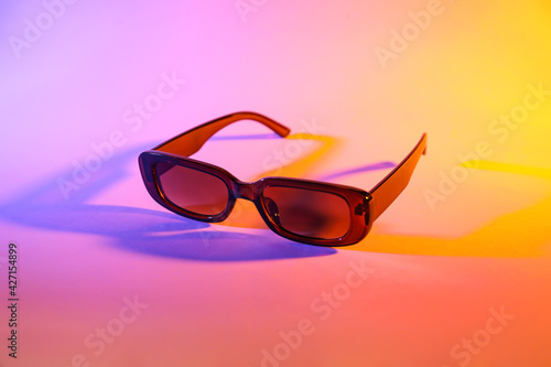 Stylish sunglasses on color background