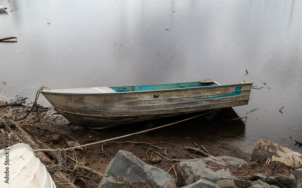 Abandoned old boat tied on the river coastline.