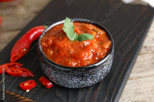 Bowl of tasty salsa sauce on wooden background