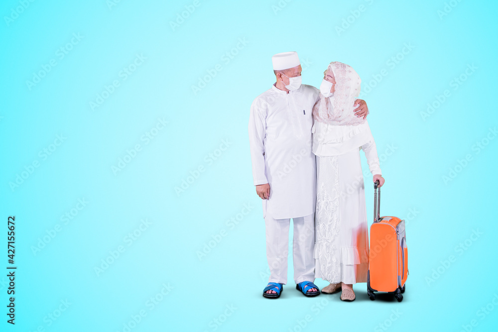 Muslim old couple in mask holding luggage on studio Muslim old couple in mask holding luggage on studio