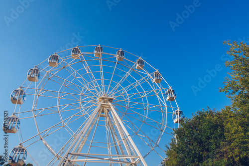 Ferris wheel on the background of the blue sky. Amusement park, fair, no people. Stock photo.