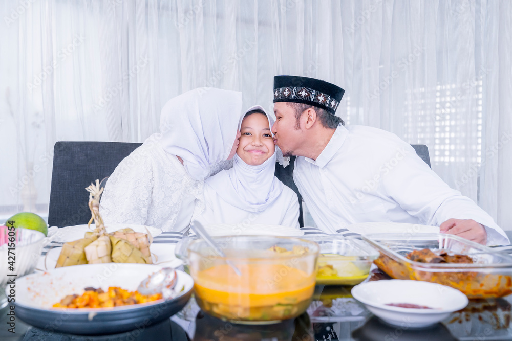 Muslim parents kiss their daughter in dining room Muslim parents kiss their daughter in dining room