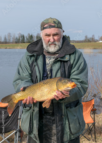 a fisherman on the shore of a lake, carp caught in the hands of a fisherman, amateur carp fishing, fishing as a hobby