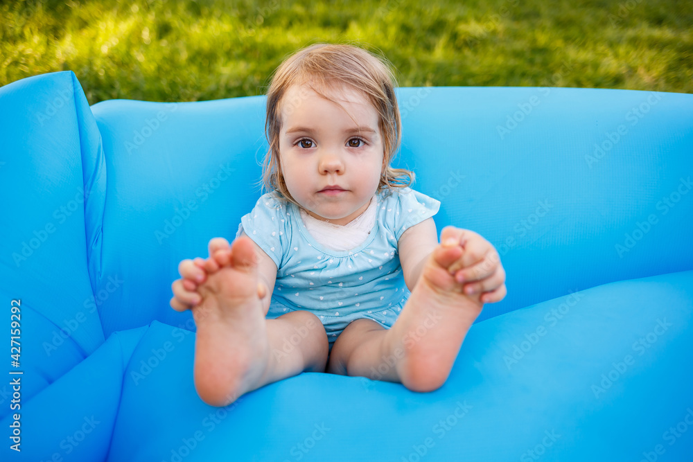 A beautiful little girl is resting and playing in the fresh air. Fooling around on a blue inflatable mattress. Smiles and rejoices A beautiful little girl is resting and playing in the fresh air. Fooling around on a blue inflatable mattress. Smiles and rejoices