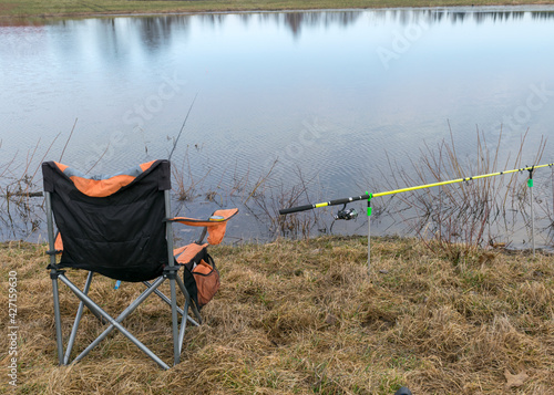 a fisherman's chair and fishing rods on the lake shore, fishing as a hobby, early spring in nature