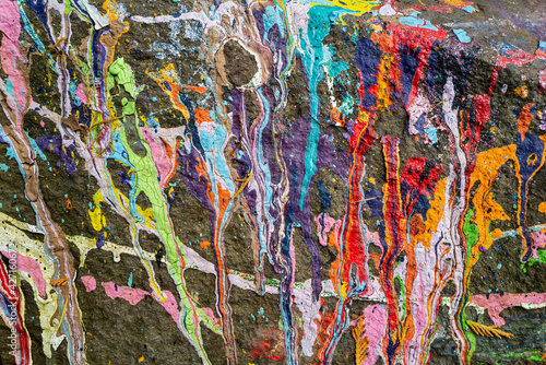 Many colors of paint spilled on a rock