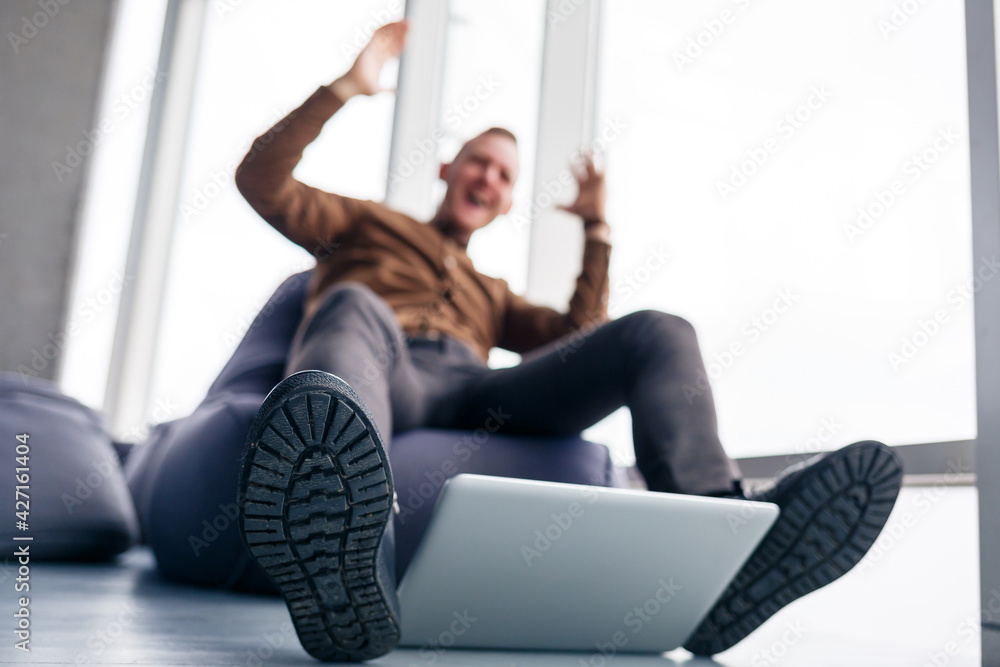 A man's foot in shoes is near the laptop. Man wants to step on his laptop