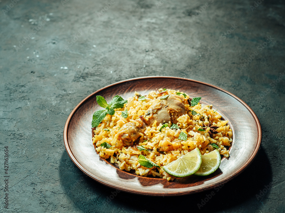 Pakistani food - biryani rice with chicken on plate. Delicious hyberabadi chicken biryani on dark background. Copy space for text or design