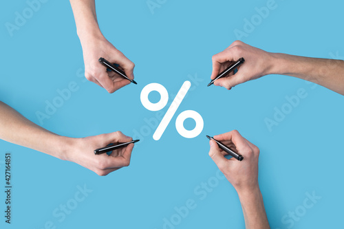 Several, four hands draw a percentage icon with a marker.nterest rate financial and mortgage rates concept. Symbol of increasing revenue, profit, EBIT and another positive growth in business. photo