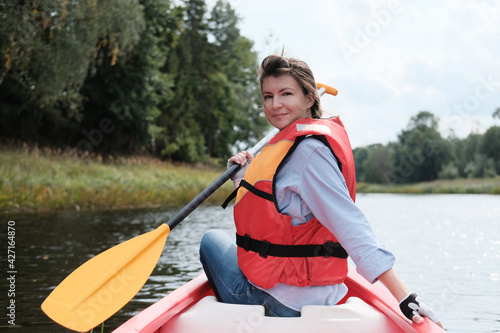 Girl smiling with a paddle on a kayak on the background of the river