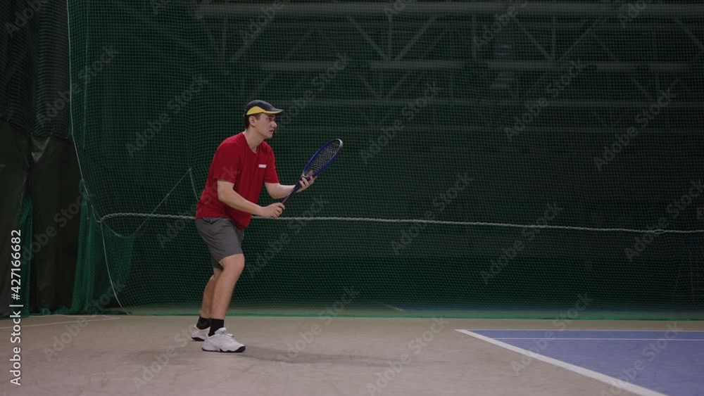 adult professional tennis player is waiting serve of opponent, hitting ball by racquet on indoor court adult professional tennis player is waiting serve of opponent, hitting ball by racquet on indoor court