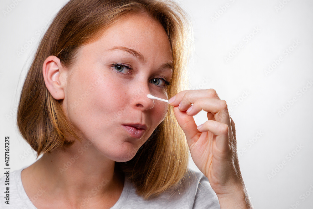 Portrait of a young woman smearing medicine on a pimple on her nose. White background. Acne and pimples concept Portrait of a young woman smearing medicine on a pimple on her nose. White background. Acne and pimples concept