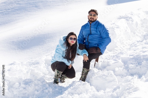 Couple in warm clothing spending leisure time on snow during ski holiday photo