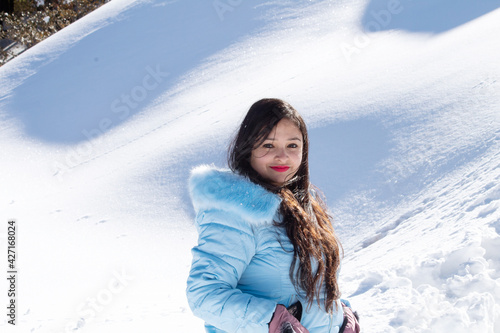 Profile of beautiful woman in hooded winter coat on snowcapped mountain photo