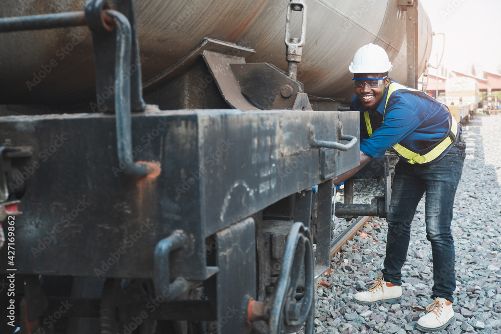 African machine engineer technician wearing a helmet, groves and safety vest is using a wrench to repair the train African machine engineer technician wearing a helmet, groves and safety vest is using a wrench to repair the train