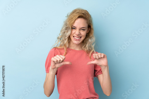 Wall Mural Young blonde woman isolated on blue background proud and self-satisfied