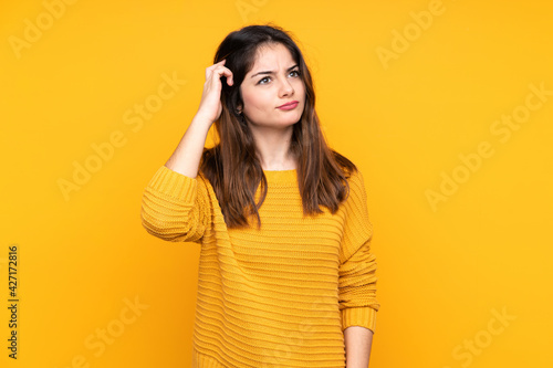 Young caucasian woman isolated on yellow background having doubts and with confuse face expression