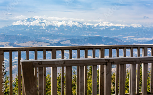 View of the Tatra mountain range from behind a wooden balustrade on an observation tower built on the Radziejowa peak in Beskid Sadecki. This peak is on the list of the Crown of Polish Mountains. photo