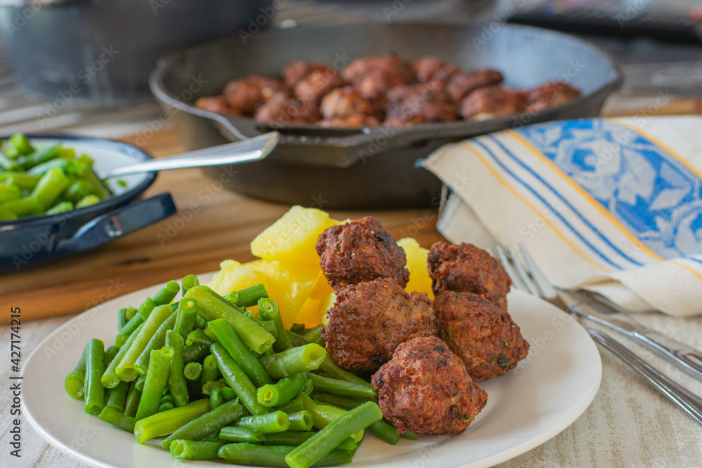 Meatball dinner with green beans and potatoes served on a plate