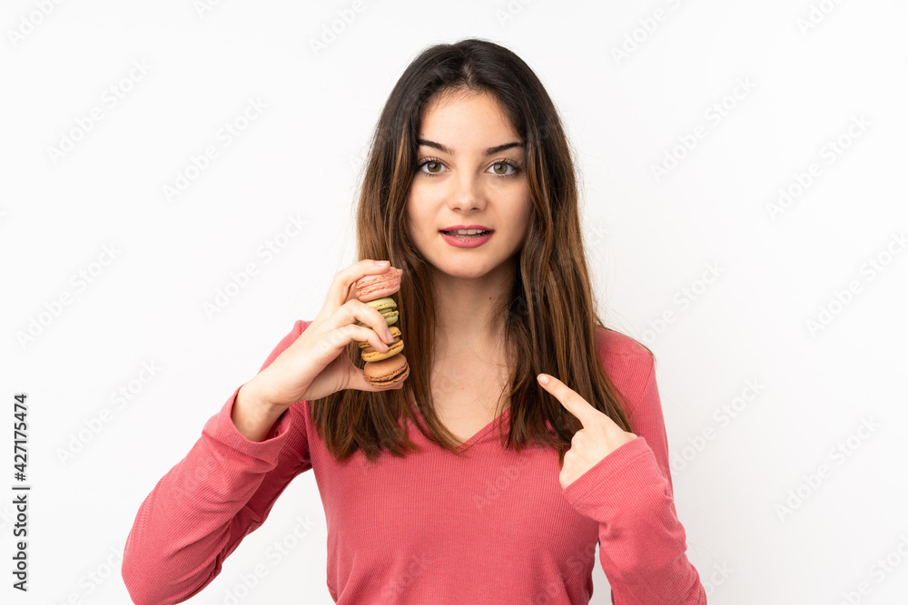 Young caucasian woman isolated on pink background holding colorful French macarons with surprise expression Young caucasian woman isolated on pink background holding colorful French macarons with surprise expression