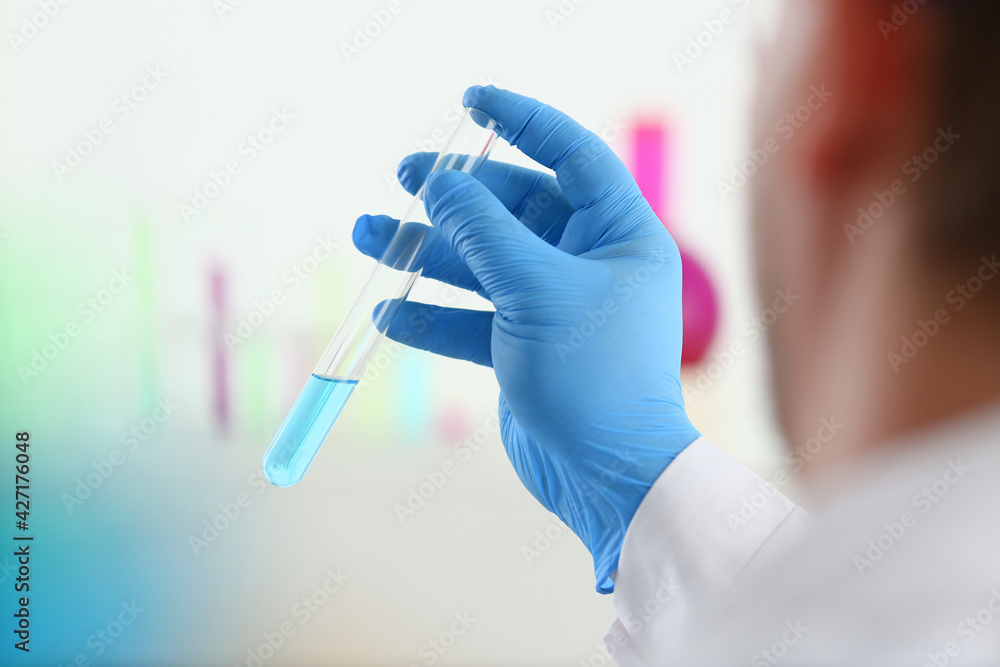 A male chemist holds test tube of glass in his hand overflows A male chemist holds test tube of glass in his hand overflows