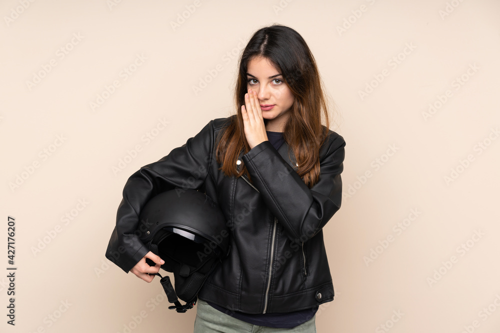 Woman with a motorcycle helmet isolated on beige background whispering something