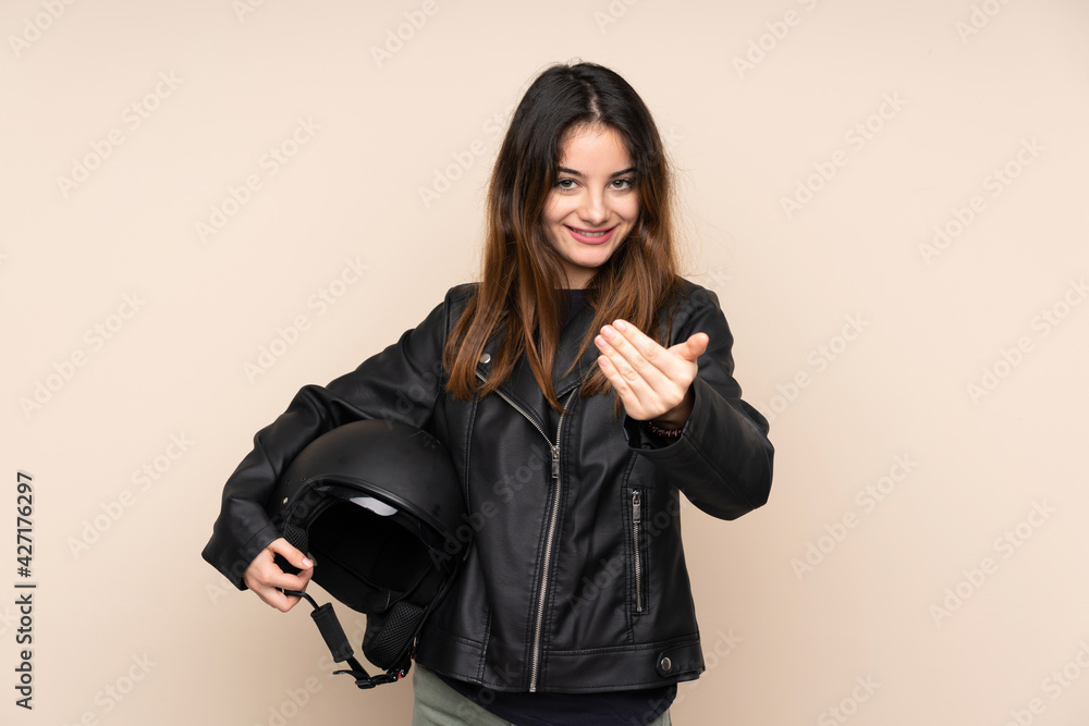 Woman with a motorcycle helmet isolated on beige background inviting to come Woman with a motorcycle helmet isolated on beige background inviting to come