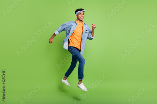 Profile photo of guy jump run look empty space wear headband denim shirt footwear isolated green color background