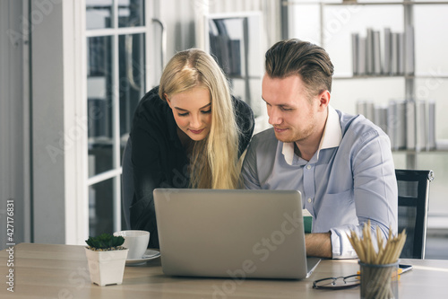 Young business man and woman working from home-office with morning sunshine. They are communicating in social network and searching information online.