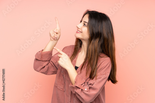 Young caucasian woman isolated on pink background pointing with the index finger a great idea