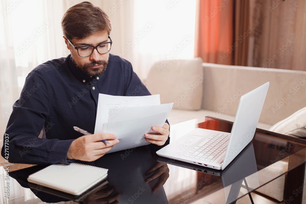 Entrepreneur works with a laptop and keeps a document in a home office Entrepreneur works with a laptop and keeps a document in a home office
