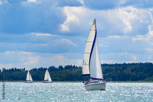 Sailing yacht in the lake with gloomy sky before the rain. Yacht sailing on the lake against a blue sky with clouds. Sailboat vacations on a lake