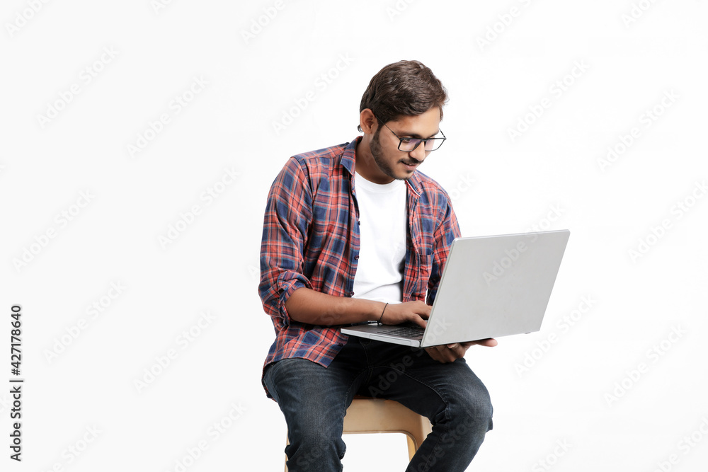 Indian college student using laptop on white background.