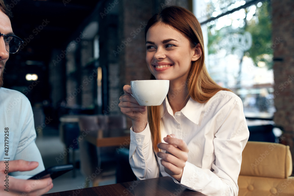 woman drinking coffee at the table next to a man work colleague technology woman drinking coffee at the table next to a man work colleague technology