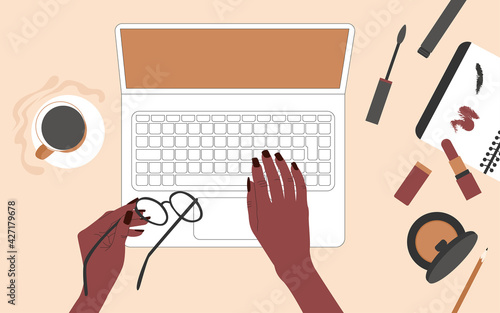 Hands of an African American woman behind a laptop. There is coffee and women's make-up supplies on the table. Top view. Flat vector illustration