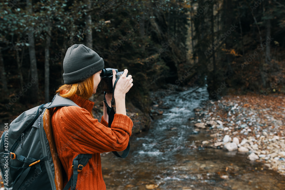 woman with a camera on nature in the mountains near the river side view woman with a camera on nature in the mountains near the river side view