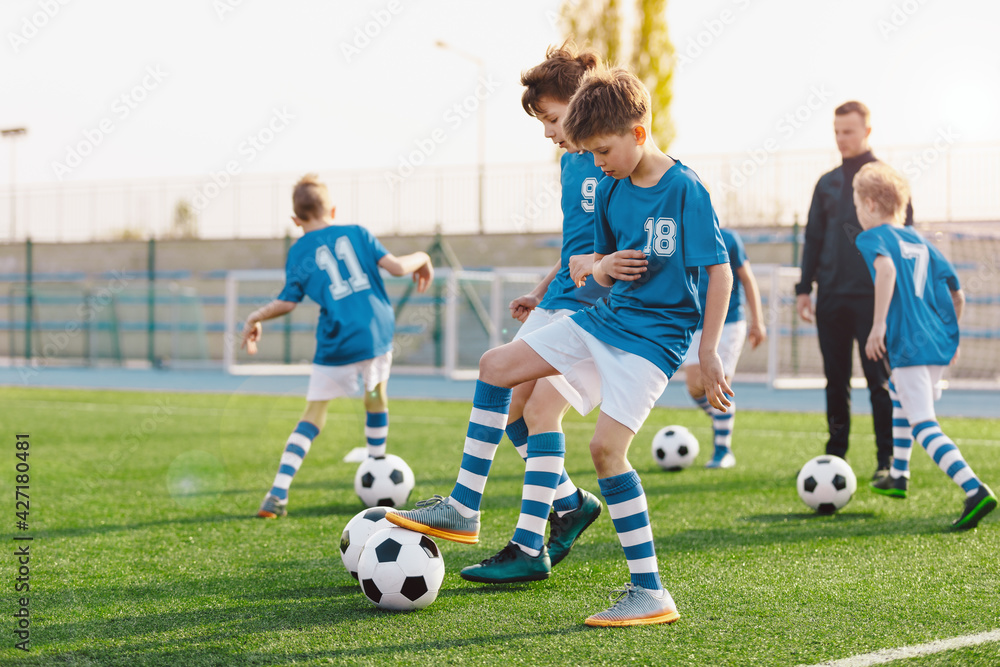 Obraz premium Kids playing and competing on sports soccer training. Happy children kicking balls on school sports field