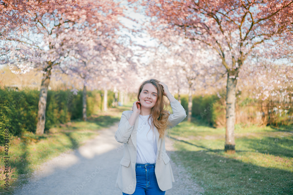Portrait of a young beautiful, curly-haired woman in a blooming sakura garden. Spring. Portrait of a young beautiful, curly-haired woman in a blooming sakura garden. Spring.