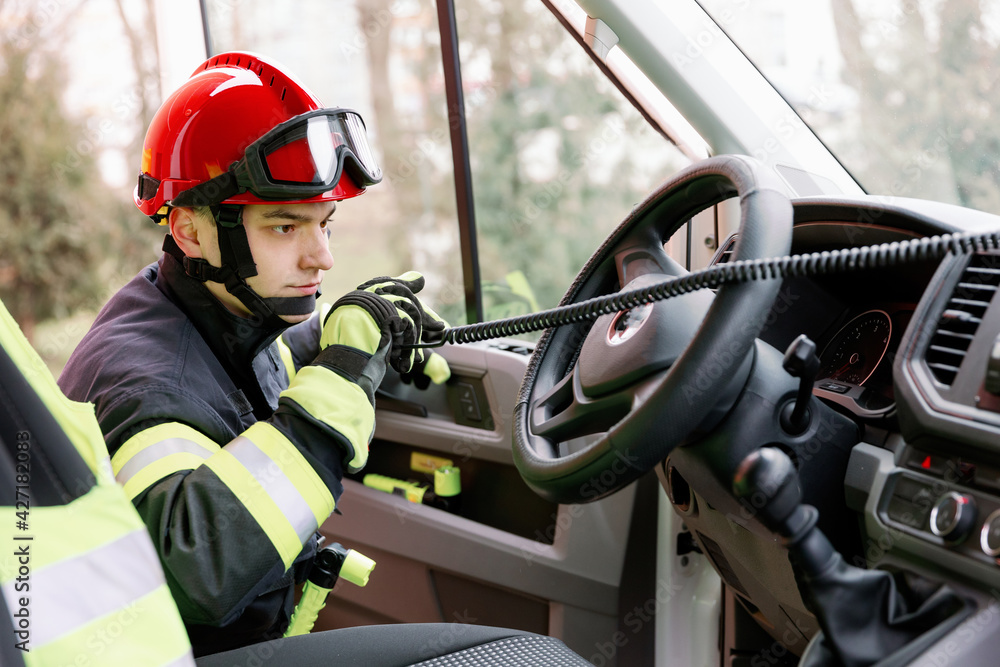 A man of strong physique in uniform and helmet stands by a rescue vehicle. A man of strong physique in uniform and helmet stands by a rescue vehicle.