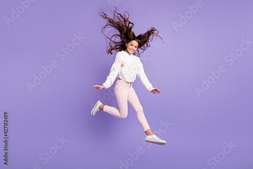 Full length photo of young crazy girl have fun enjoy jump active wind hair isolated over violet color background