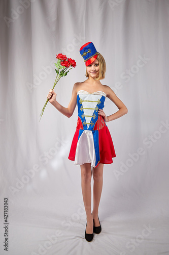 A young teenage girl in a stylized uniform of a grenadier soldier or a cheerleader posing in a studio