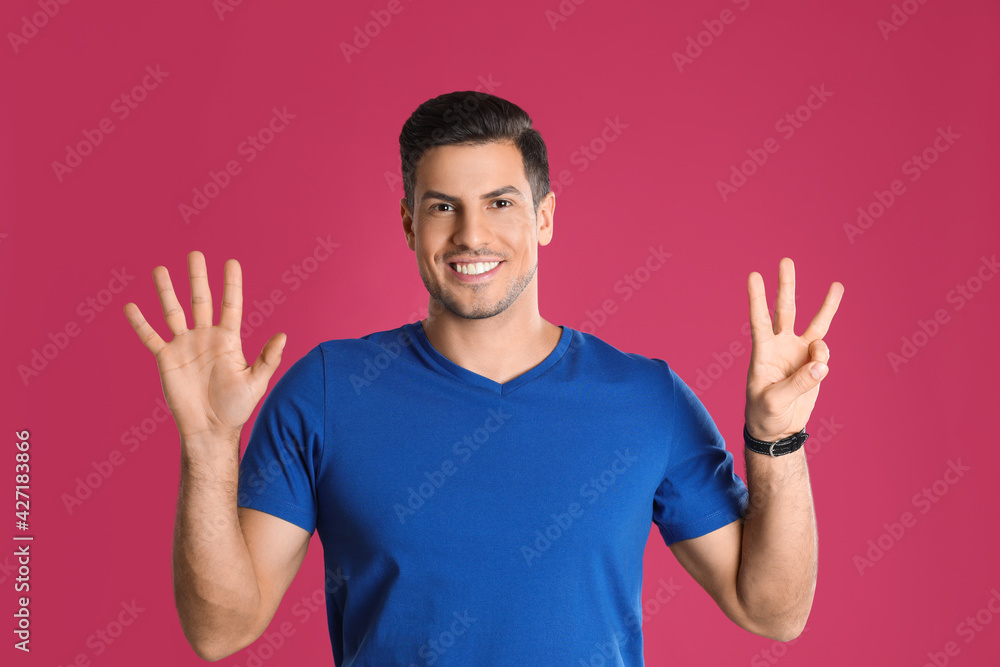 Naklejka premium Man showing number eight with his hands on pink background