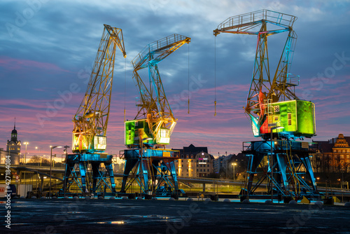 Historic port cranes in Szczecin illuminated with effective illumination against the beautiful evening sky