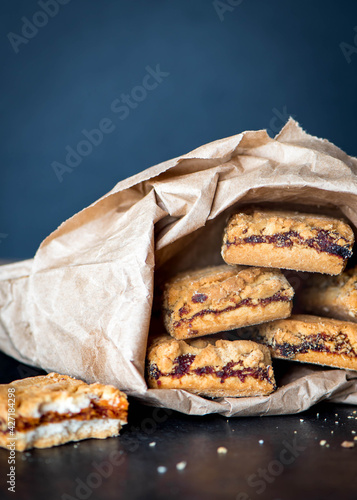 Square cookie with jam in a paper bag on dark background, with copy space photo